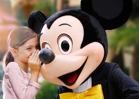 Girl whispering to Mickey Mouse at Disney theme park