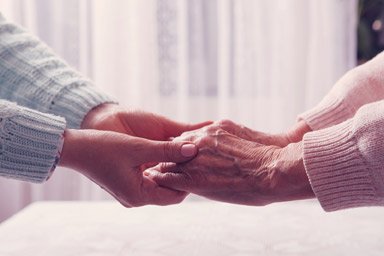 Carer holding hands with elderly patient